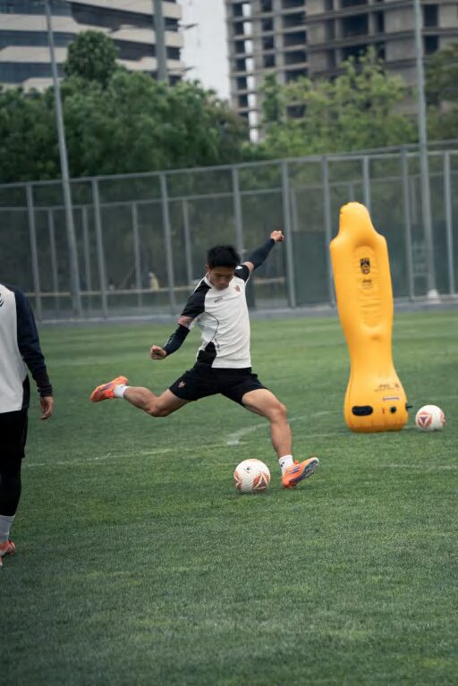 Player striking a ball during training in a GOINTO training top